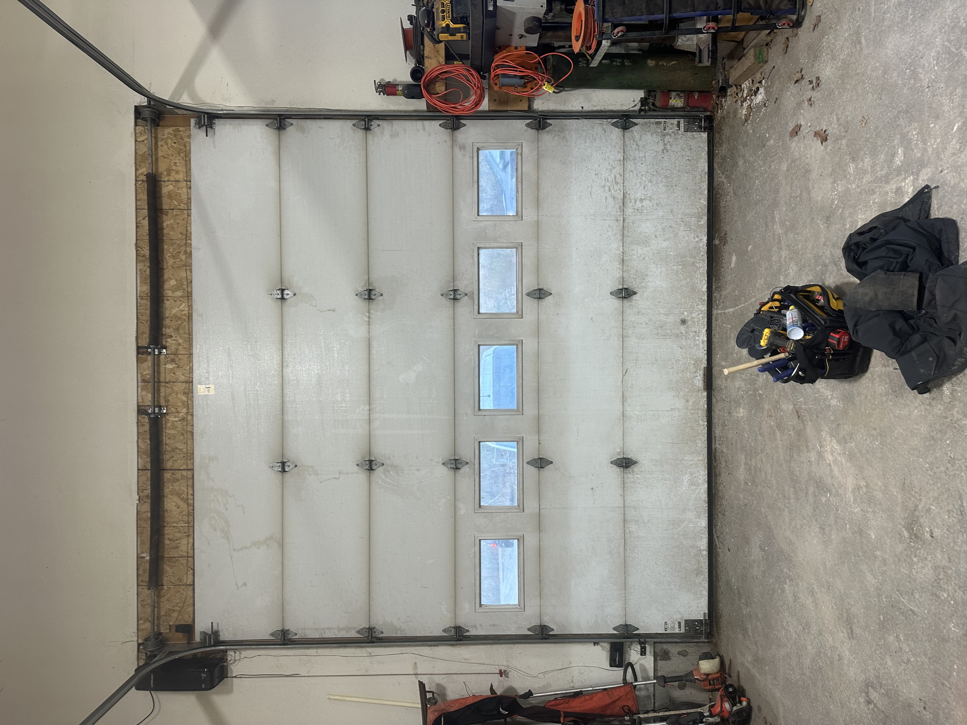 Residential garage door with window panels during installation showing tracks and hardware